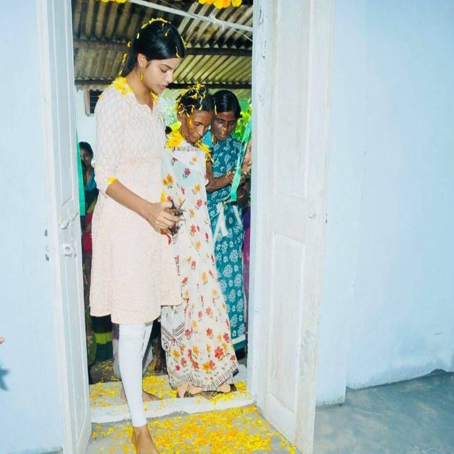 Sakkubhai stepping into her new home with the founder, the doorway decorated with flowers
