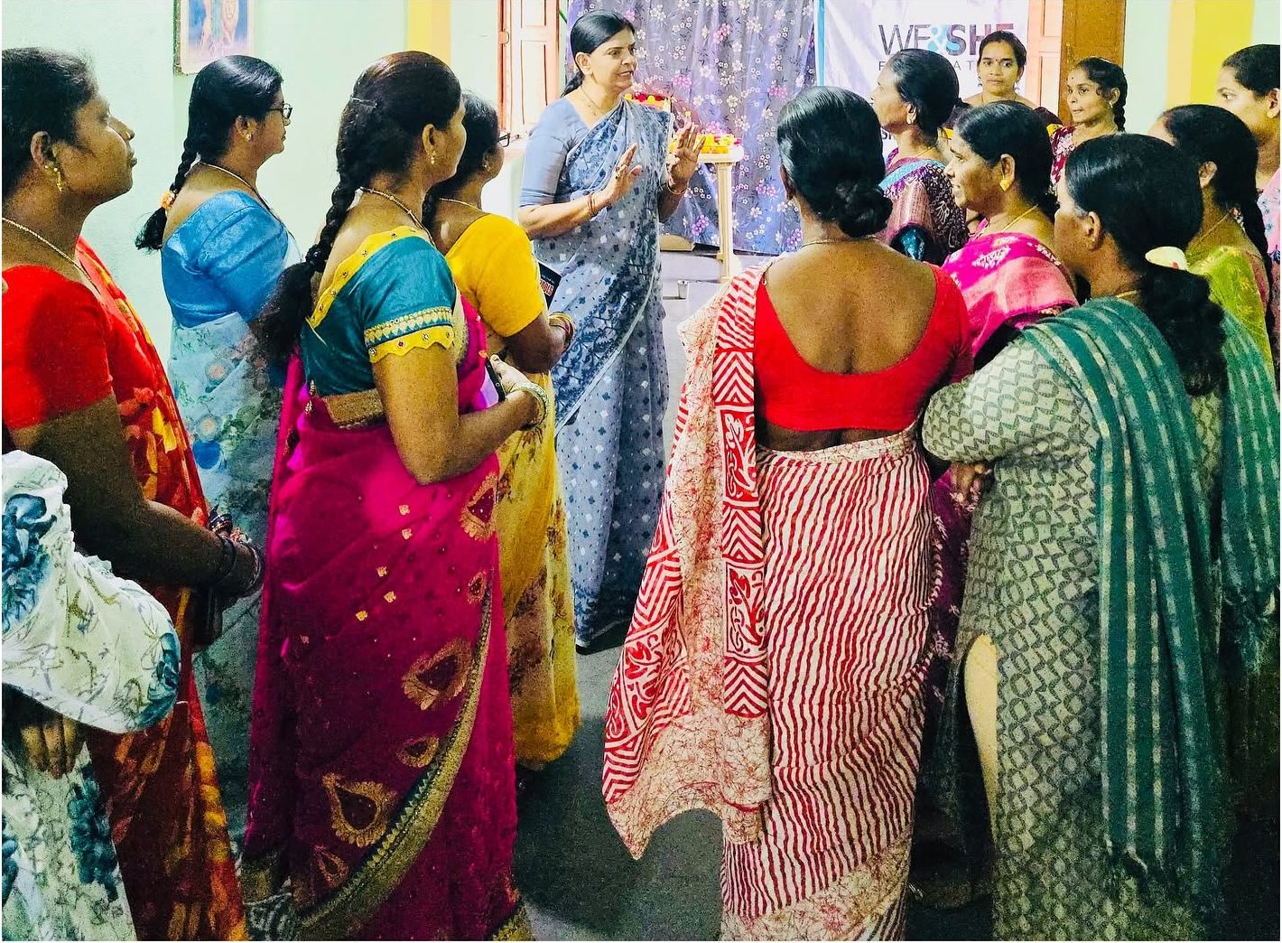 Women in colourful saris stand in a circle listening at the skill centre