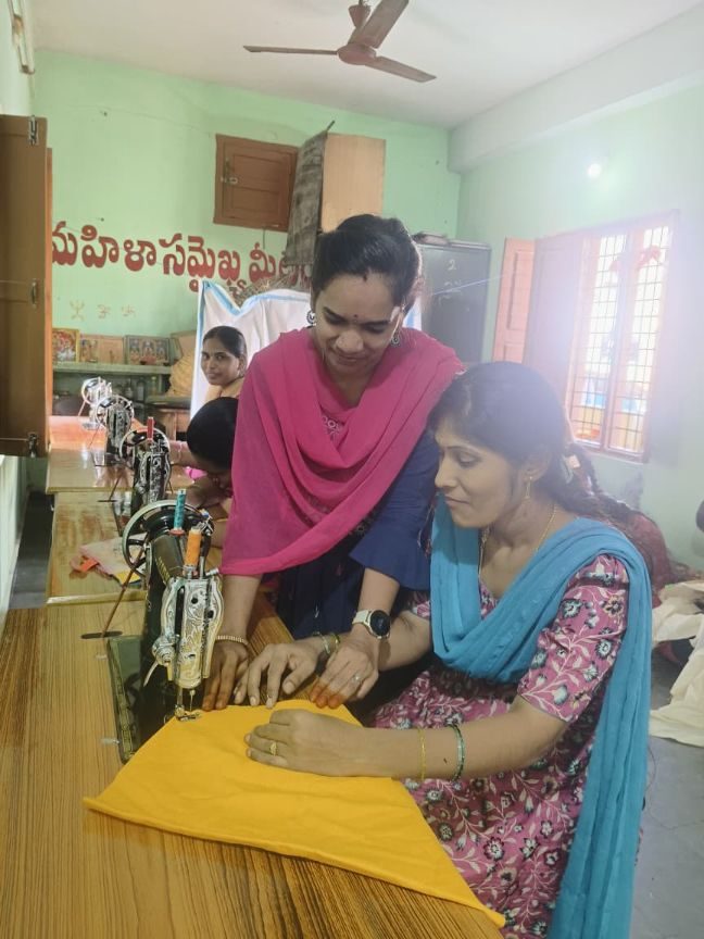 A trainee learning to cut cloth with the trainer beside her