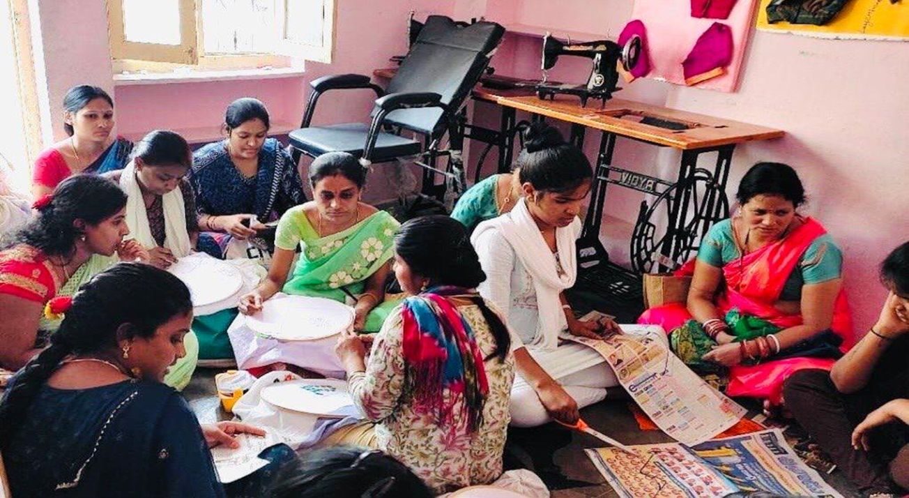 Women at work around a table covered in fabric and patterns